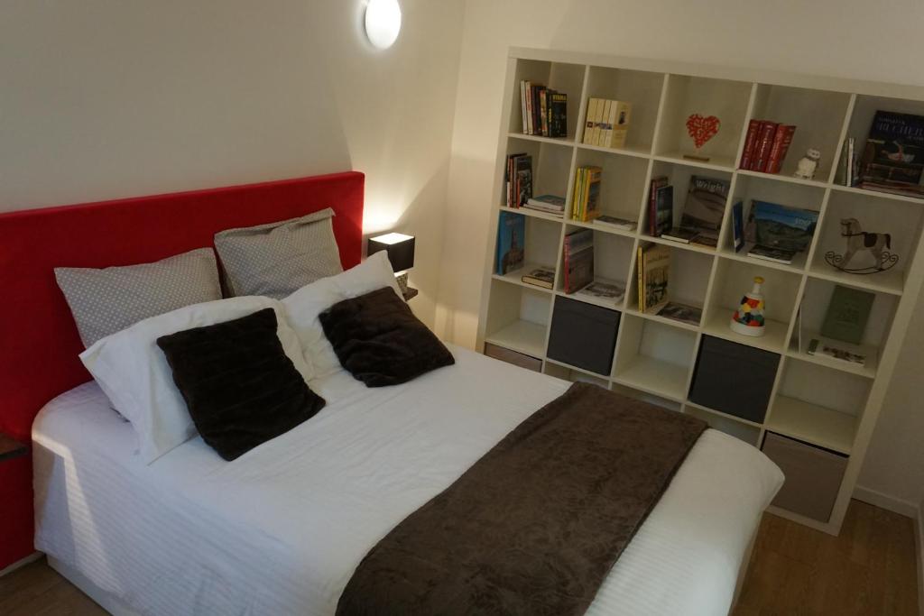 聖米耶勒的住宿－Appartement Larzilliere，一间卧室配有一张带红色床头板和书架的床