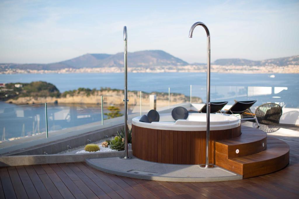 bañera de hidromasaje en una terraza con vistas al agua en Hotel Cala Moresca, en Bacoli