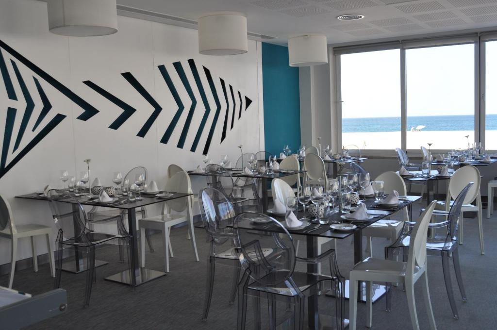 a dining room with tables and chairs and windows at Hotel Mar Bravo in Nazaré