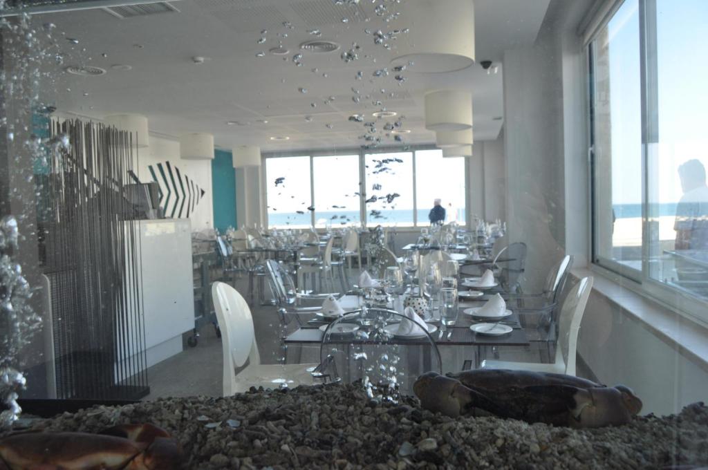 a dining room with a table and chairs with the ocean at Hotel Mar Bravo in Nazaré