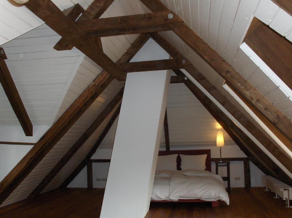 Zimmer im Dachgeschoss mit einem weißen Bett und Holzbalken in der Unterkunft CARLS KATE in Grömitz an der Ostsee in Grömitz