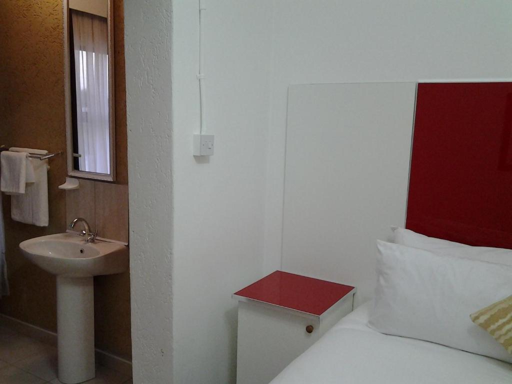 a small bathroom with a bed and a sink at Keeme-Nao Self Catering Apartments in Gaborone
