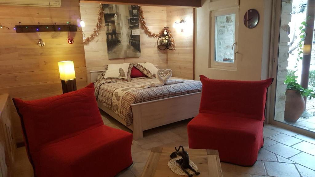 a bedroom with a bed and two red chairs at L'Olivier Chez Mamé Marthe in Vallon-Pont-dʼArc