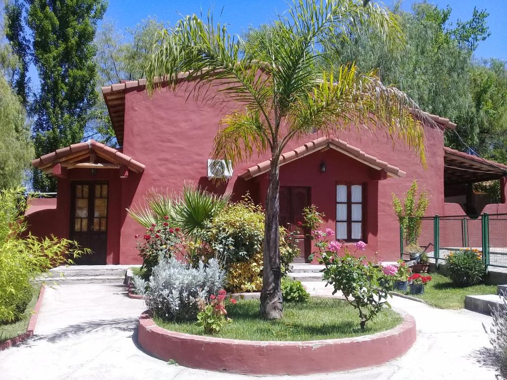 una casa rosa con una palmera delante de ella en El Alto de las Paredes en San Rafael
