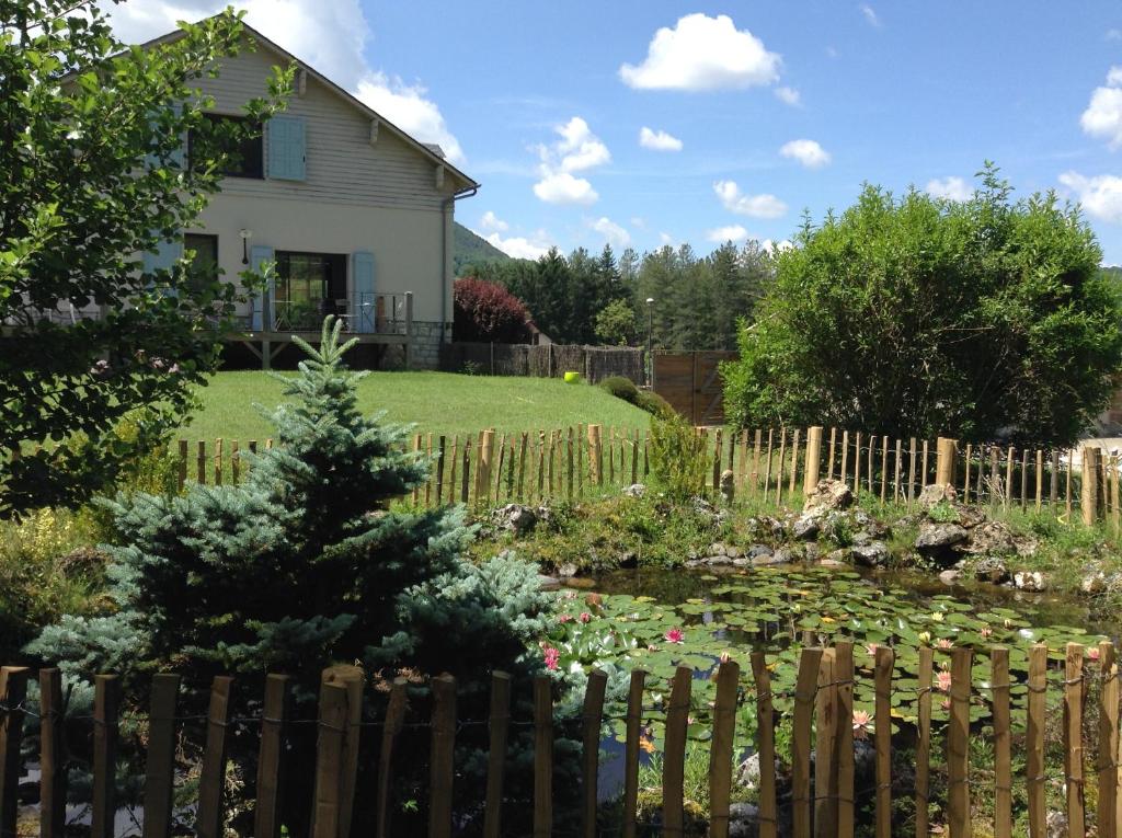 a yard with a fence and a pond in front of a house at D'un jour à l'autre in Banassac