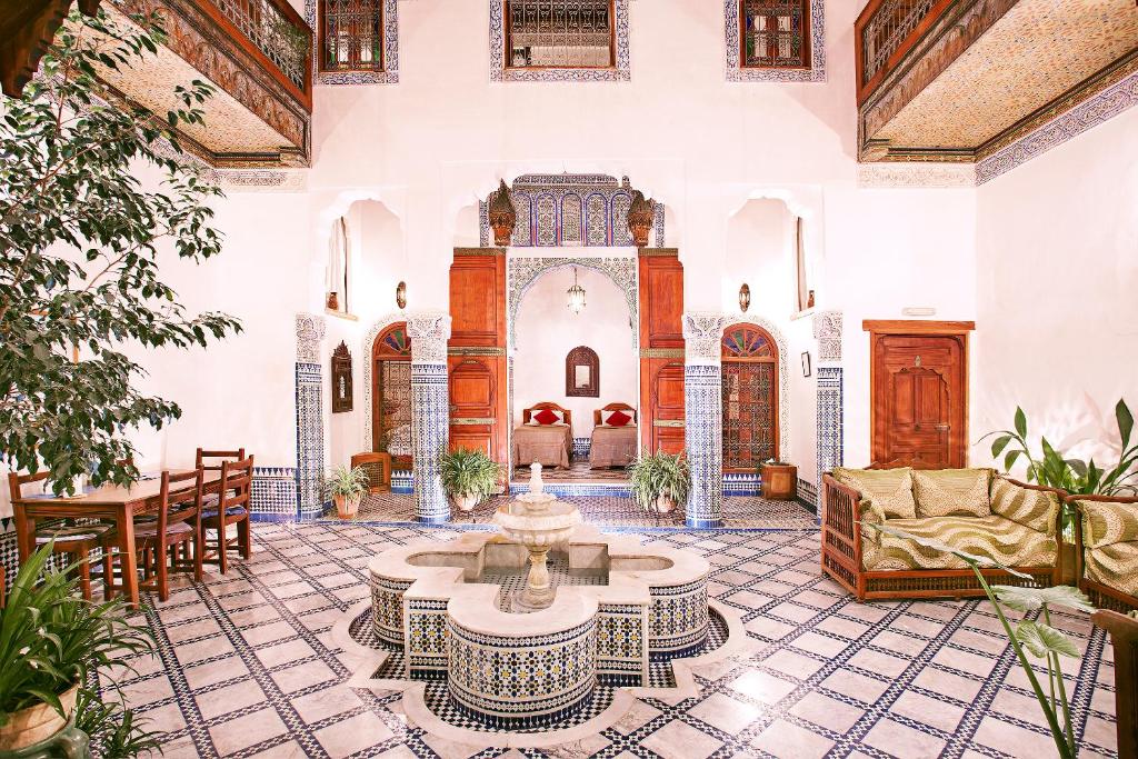 een grote woonkamer met een tafel en stoelen bij Dar Drissi in Fès