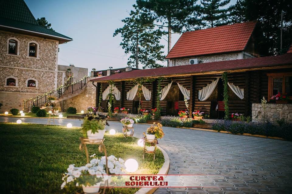 a building with a pavilion with flowers in a yard at Curtea Boierului Hotel in Peresecina