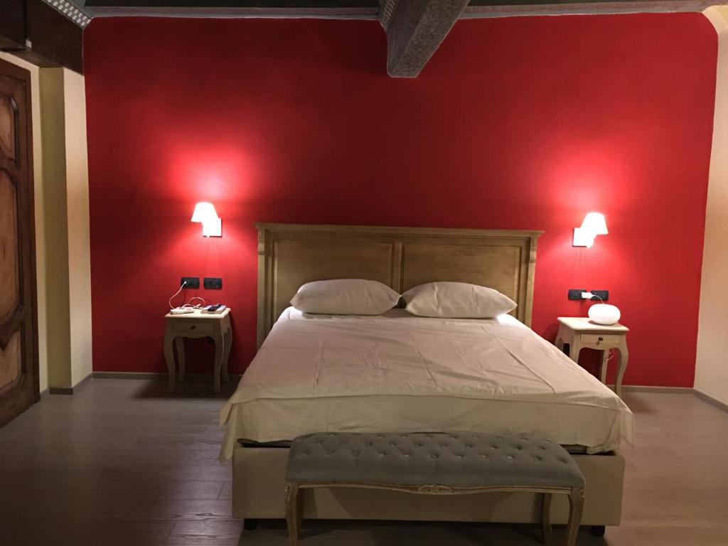 um quarto com uma parede vermelha com uma cama e duas mesas em Visione Strada Maggiore 62 em Bolonha