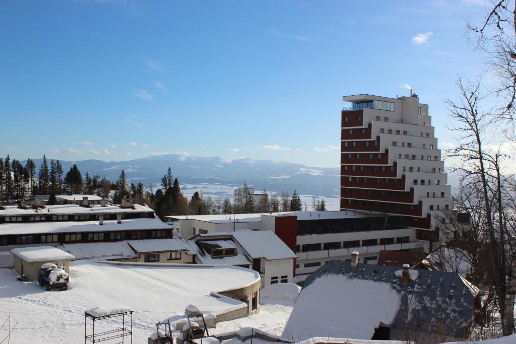 pokryte śniegiem miasto z budynkami i wysoki budynek w obiekcie Apartman Panorama 329 w Szczyrbskim Plesie