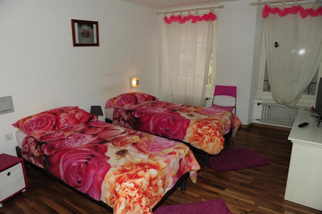 a bedroom with two beds with red sheets at Hotel Restaurant Au Chasseur in Orbe