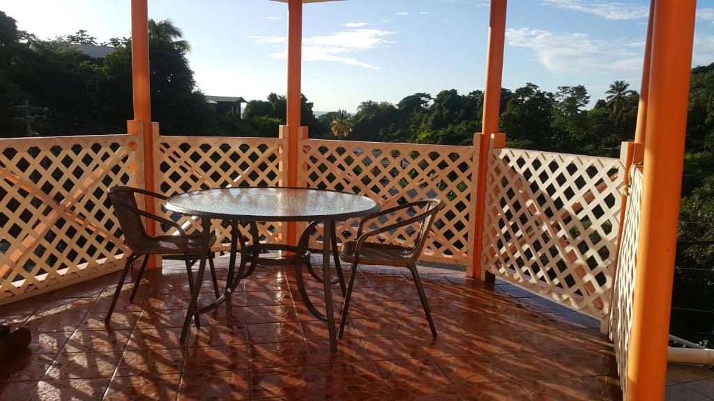 a glass table and two chairs on a porch at Golden Apple Cottage in Castara