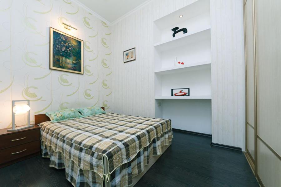 ein Schlafzimmer mit einem Bett mit einer karierten Decke in der Unterkunft Двухкомнатная студио на Саксаганского in Kiew