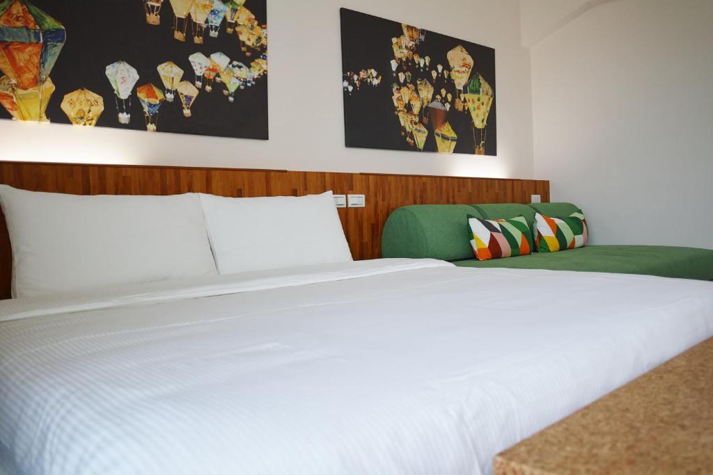 a bedroom with a white bed and a green couch at I Like B&B in Taitung City