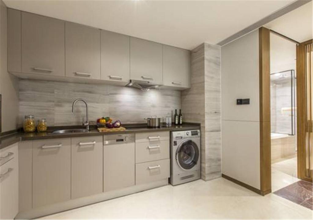 a kitchen with white cabinets and a washing machine at Ascott Riverside Garden Beijing in Beijing