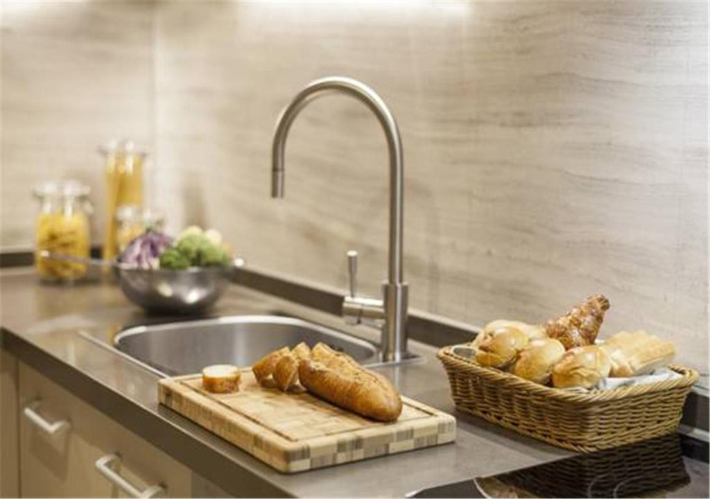 a kitchen counter with a sink and a basket of bread at Ascott Riverside Garden Beijing in Beijing