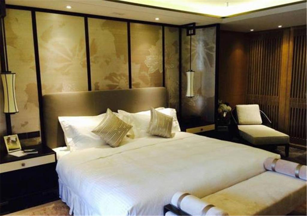a bedroom with a large white bed and a chair at Ascott Riverside Garden Beijing in Beijing