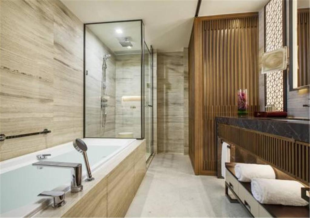 a bathroom with a tub and a shower and a sink at Ascott Riverside Garden Beijing in Beijing