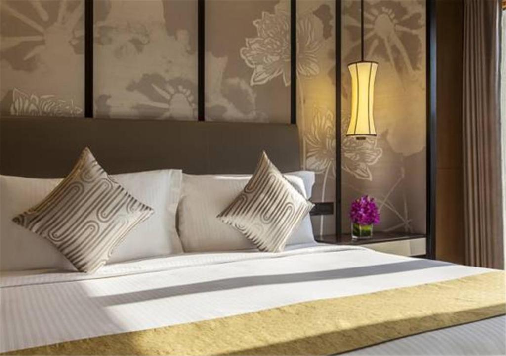 a bedroom with a white bed with pillows and a lamp at Ascott Riverside Garden Beijing in Beijing