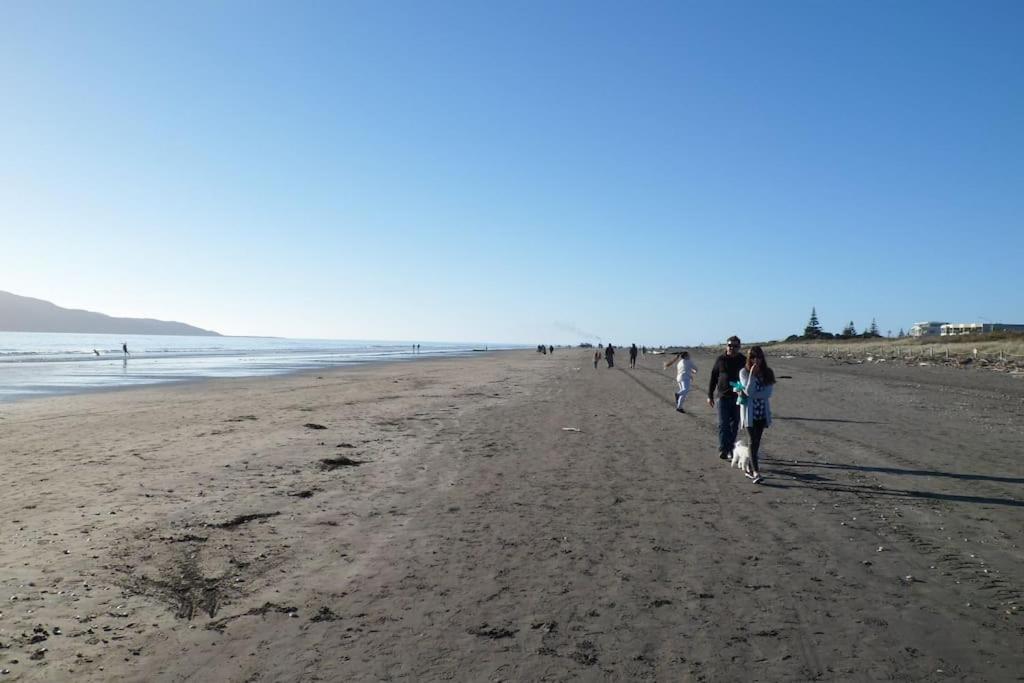 un grupo de personas caminando por la playa en Dream Escape for 2, en Paraparaumu Beach