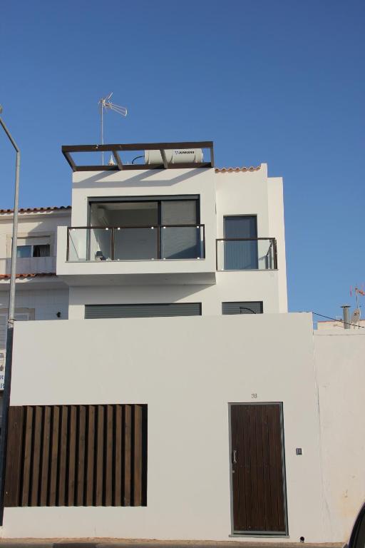 a white building with two doors and a balcony at Flamingo Beach House in Santa Luzia