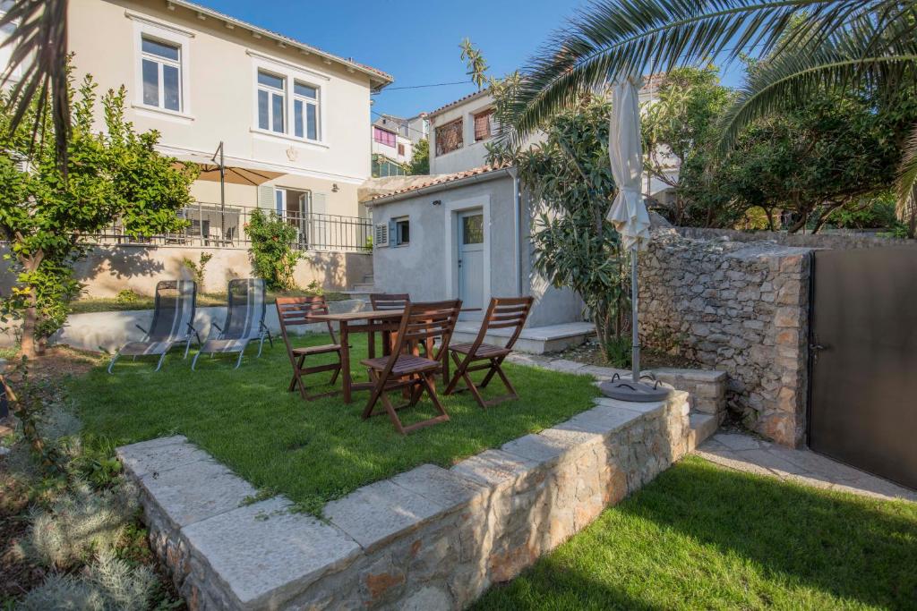a backyard with a table and chairs and an umbrella at Apartments Villa Adrienne in Mali Lošinj