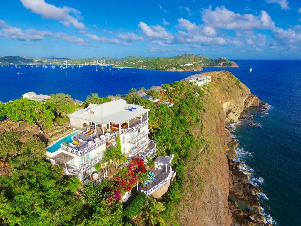 an aerial view of a house on a cliff next to the ocean at Dolcevita Cliff Private Resort by KlabHouse - Adults Only in English Harbour Town
