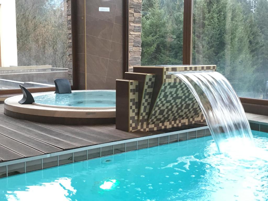 a hot tub with a waterfall in a spa with a pool at Holiday Park Orava - Hotel Orava in Dolný Kubín