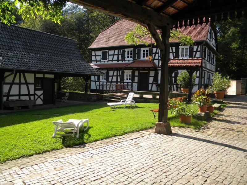 a courtyard of a house with a bench in the grass at Ferme Auberge du Moulin des Sept Fontaines in Drachenbronn