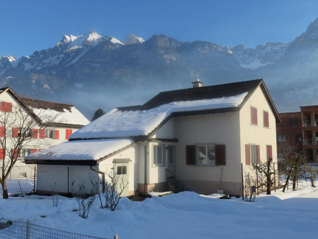 a house in the snow with mountains in the background at Ferienhaus Schils in Flums