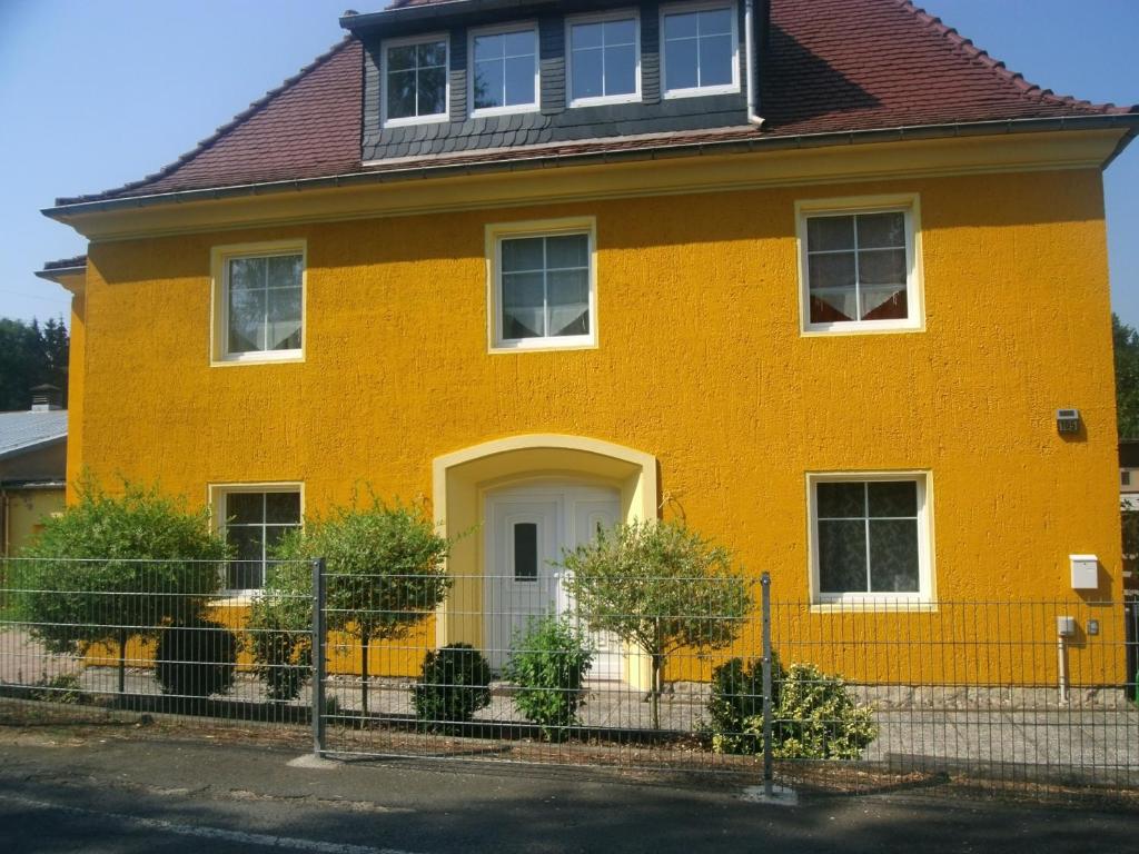 une maison jaune avec une clôture devant elle dans l'établissement Ferienhaus Meier, à Struppen