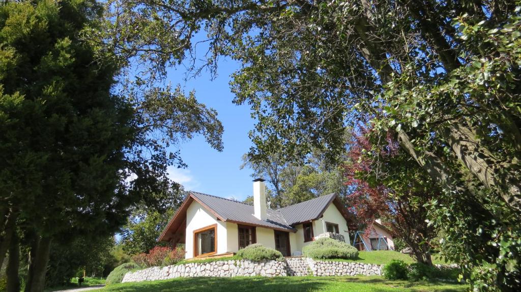 a house with a stone fence in front of it at Cabañas & Aparts Lancuyen, Villa de Montaña in Villa La Angostura