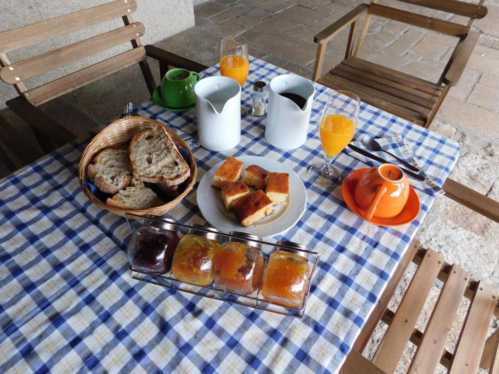 a table with a plate of bread and orange juice at Hotel Rustico Casa Do Vento in Bayo