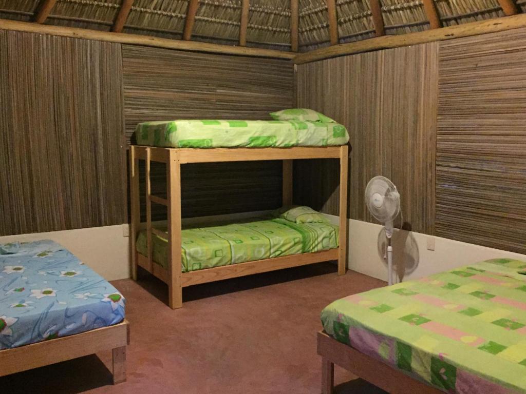 a room with two bunk beds and a fan at Mondala Hostal Carrizalillo in Puerto Escondido