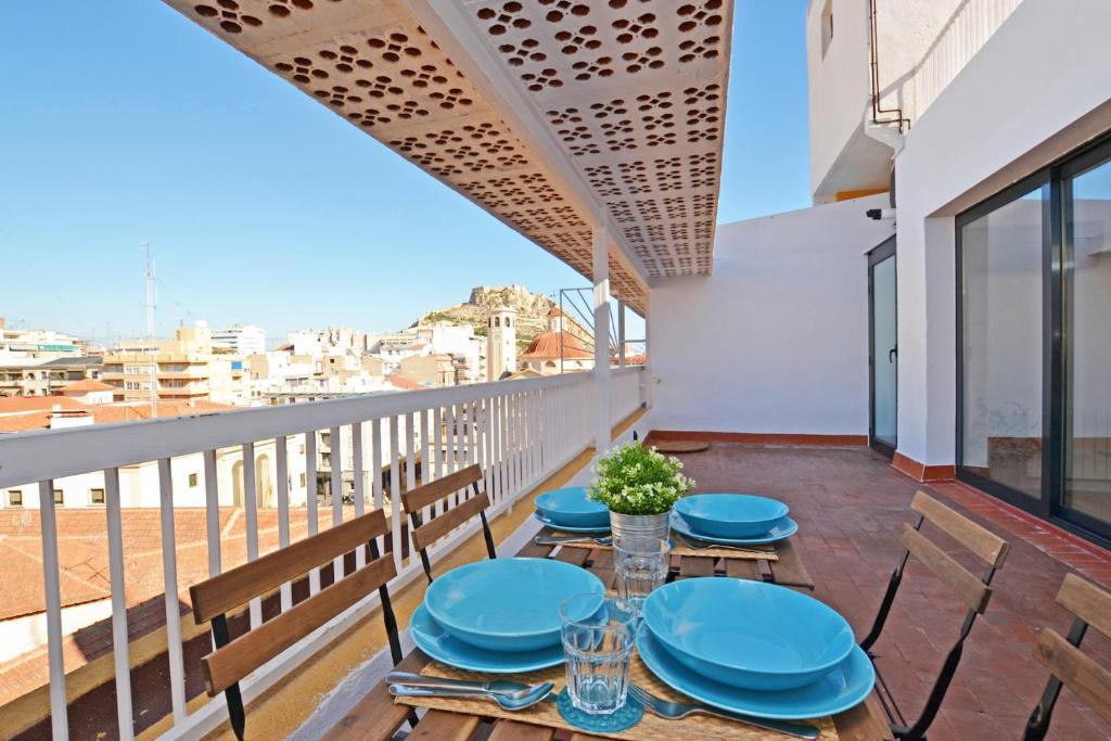 Un balcón con mesas azules y sillas con vistas. en Atico Colón 21, en Alicante