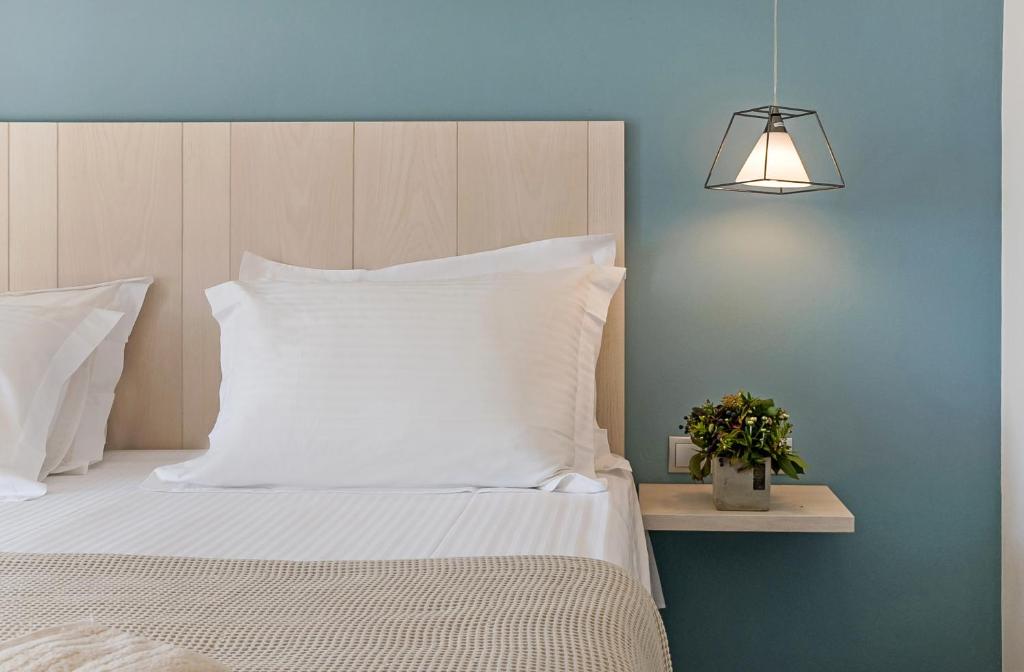 un letto con cuscini bianchi e un lampadario; di Lidea Boutique Hotel a Potamós