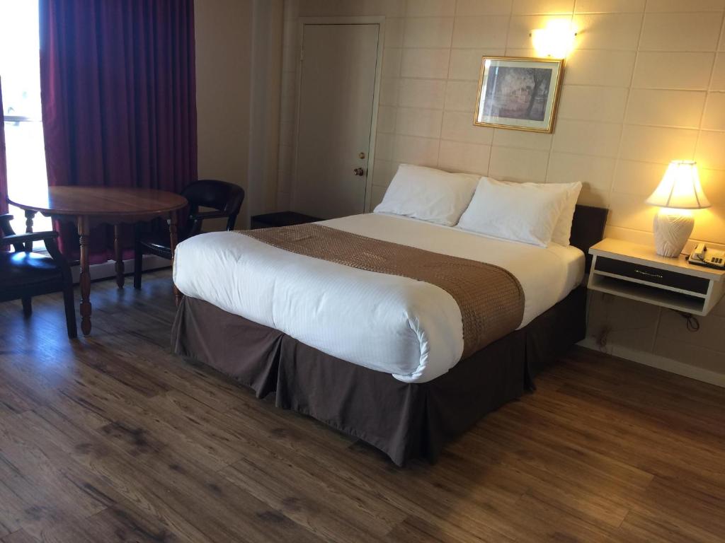 Olds的住宿－Siesta Motel，酒店客房设有一张大床和一张桌子。