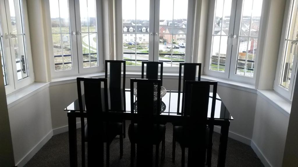 a dining room with a table and chairs and windows at Crystal Apartments in Airdrie