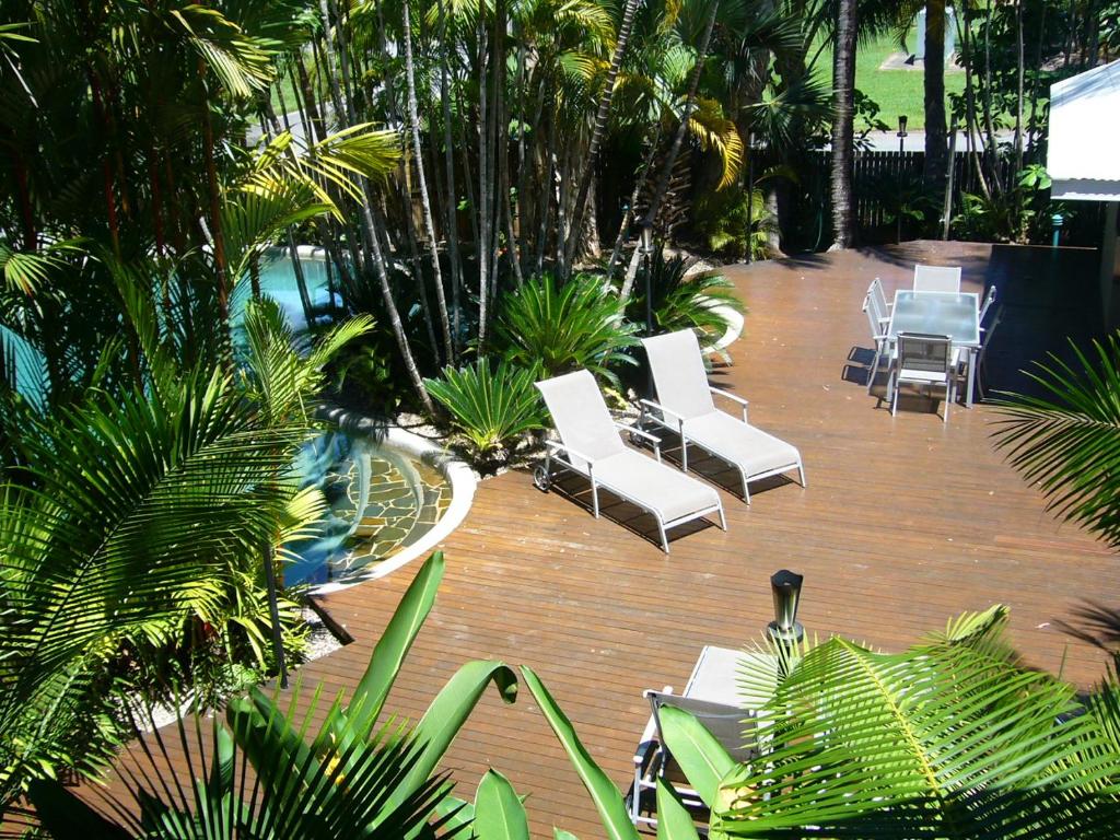 a patio with white chairs and a pool and palm trees at Port Douglas Retreat in Port Douglas