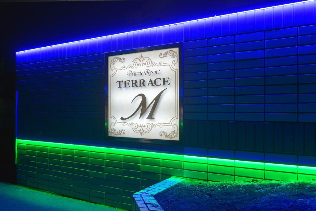 znak na ceglanej ścianie z zielonymi i niebieskimi światłami w obiekcie Terrace M Yokota Bace ( Adult Only ) w mieście Hakonegasaki