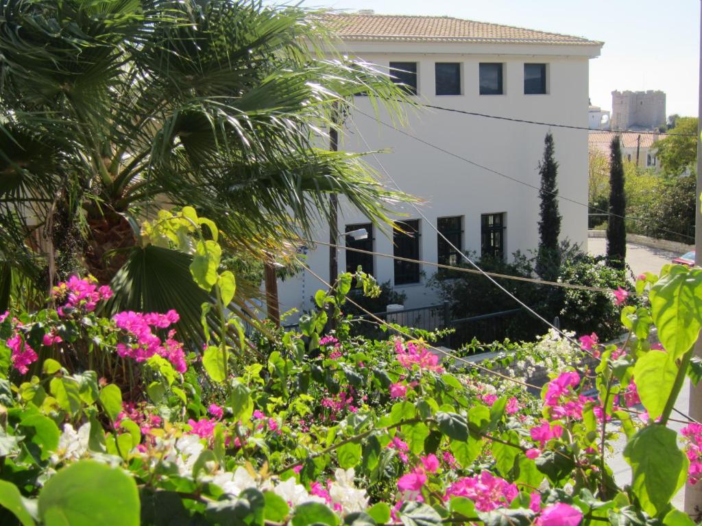a garden with pink flowers in front of a white building at Sandalis Hotel in Pythagoreio