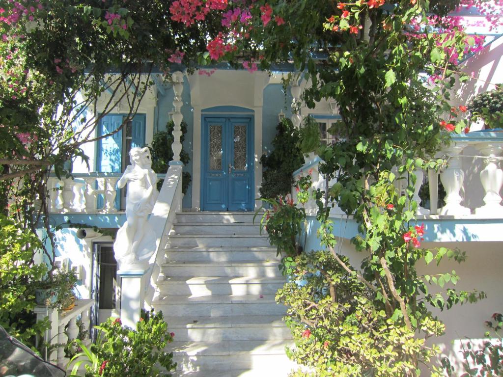 a blue door on a white house with flowers at Sandalis Hotel in Pythagoreio