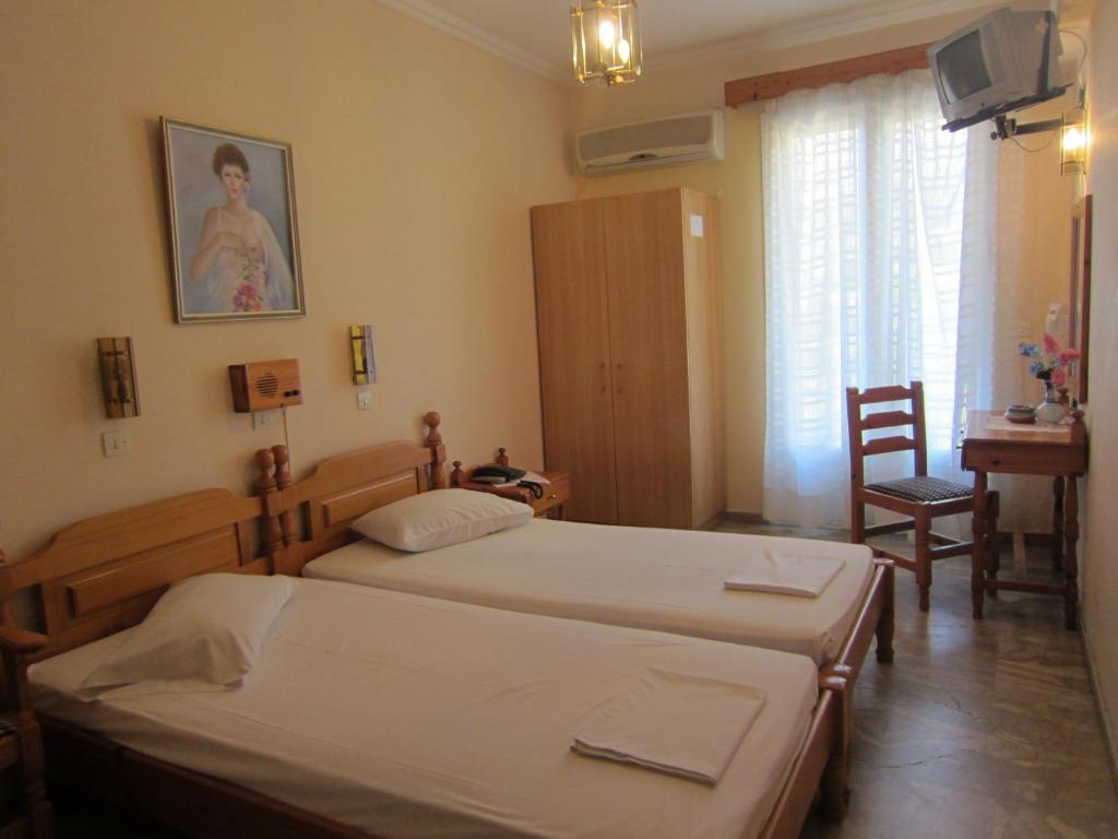 a bedroom with two beds and a table and a chair at Sandalis Hotel in Pythagoreio