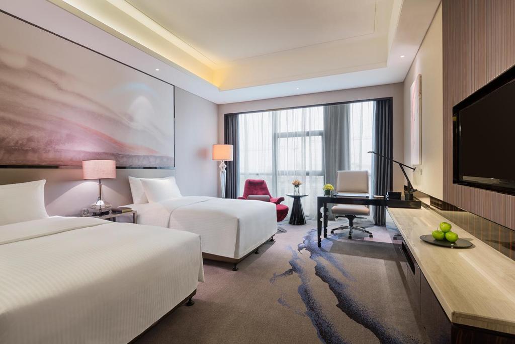 a hotel room with two beds and a flat screen tv at Wanda Realm Wuhan in Wuhan