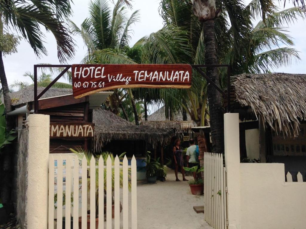 a sign for a hotel with a fence and palm trees at Village Temanuata in Bora Bora