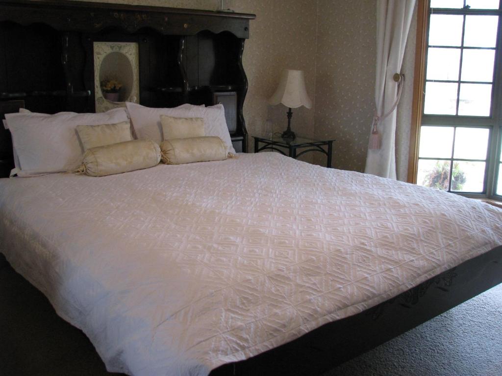 a large white bed with white sheets and pillows at Hill Top Country Guest House in Lovedale