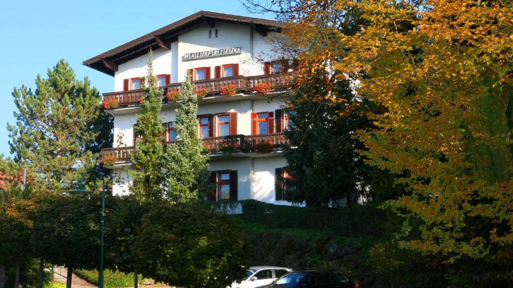 ein großes weißes Gebäude mit Balkonen und Bäumen in der Unterkunft Pension Waldfriede in Bad Tatzmannsdorf
