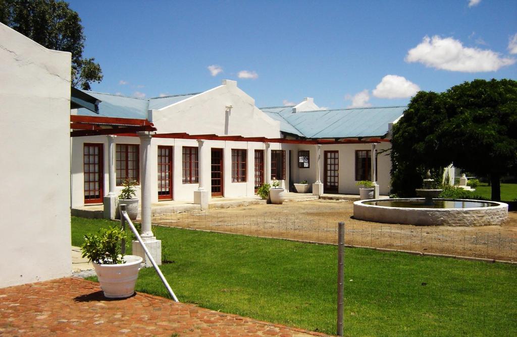 a white building with a fountain in the yard at Rhino Creek Estate in Bloemfontein