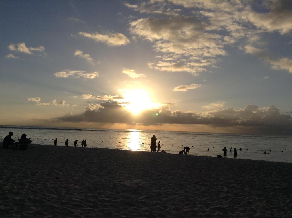 a group of people on the beach at sunset at Le Palmier C10 in Flic-en-Flac