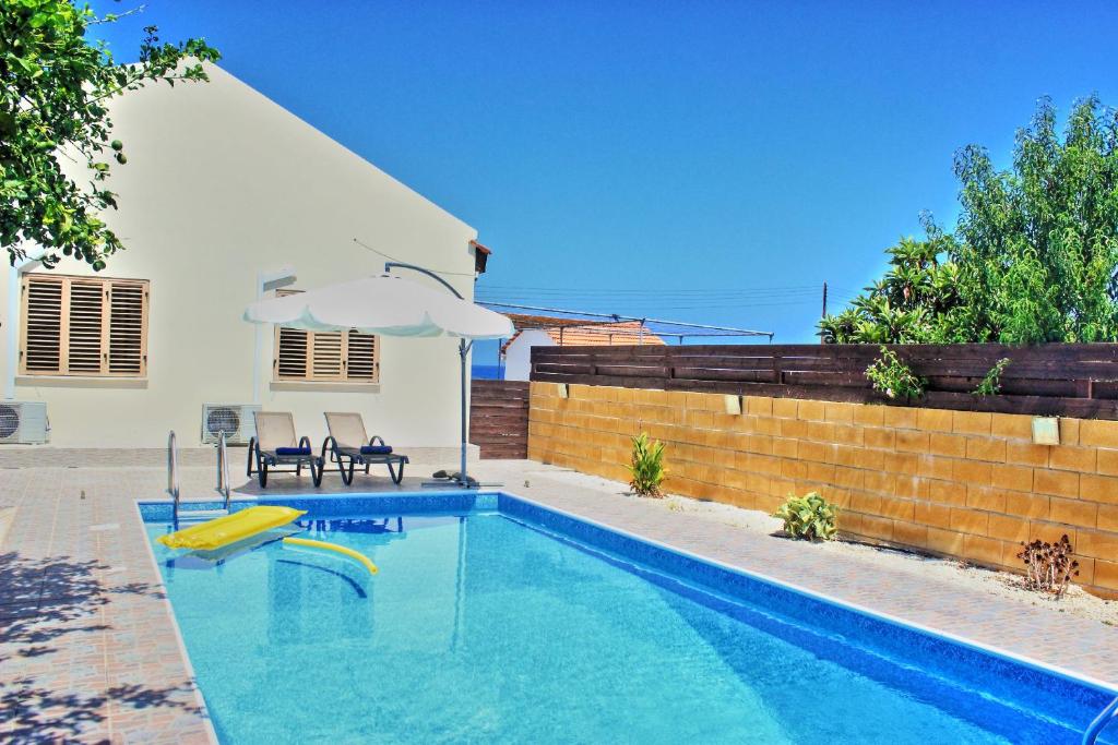una piscina con due sedie e un ombrellone di Villa Majestic ad Ayia Marina