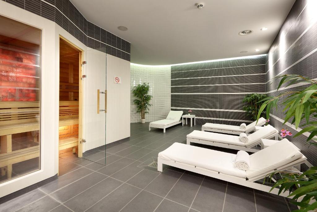 a lobby with white couches and chairs in a building at Eurostars Book Hotel in Munich